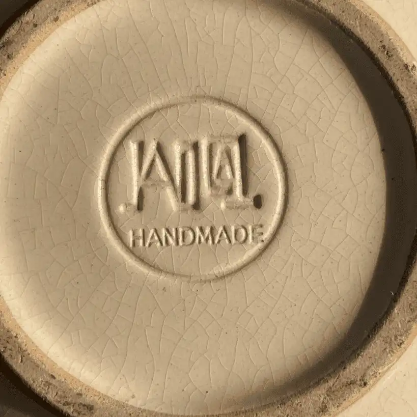 Underside of a vintage pottery jar showing an authentic incised manufacturer hallmark and natural shelf wear